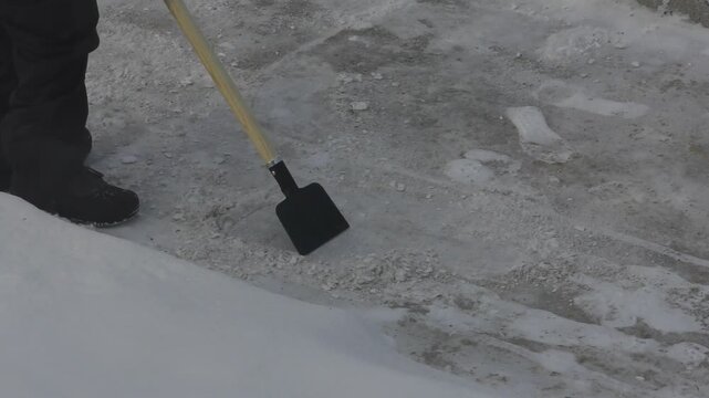 scraper removing ice from sidewalk off the pavement