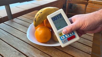 Measuring radiation levels of fruits with geiger counter on wooden table © iri.madrid.art