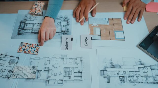 A dynamic workspace featuring hands engaged in a collaborative interior design process. Colorful sketches and plans lay spread out, displaying innovative design ideas. SACTR
