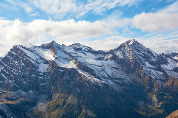 Snow-covered mountains stand as majestic white giants against sky, embodying winter's powerful alpine beauty.