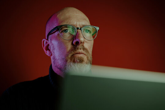 Ein Mann in den Vierzigern sitzt an einem Schreibtisch in seinem Home-Office und nutzt Anwendungen k&uuml;nstlicher Intelligenz auf seinem Laptop. 