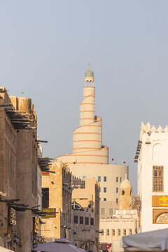 Doha, Qatar - 21 February 2025: View of the Fanar Qatar Islamic Cultural Center's distinctive spiral mosque amidst traditional buildings, bathed in the warm glow of the setting sun.