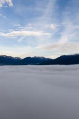 Fototapeta premium Cloud Sea Over Mountain Ridge at Sunrise: Serene Sky, Mist, and Distant Peaks