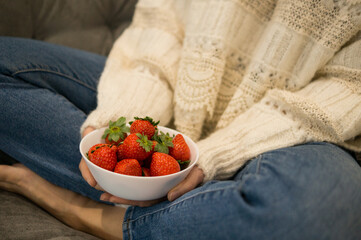Cozy winter afternoon at home, woman in fuzzy sweater eating healthy red berries