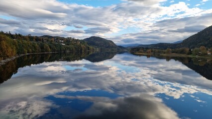 Reflection of clouds and trees on calm water in a valley during daytime