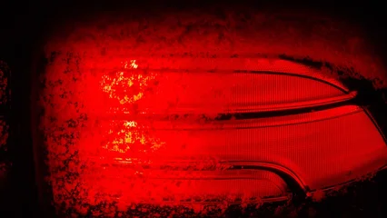 Fotobehang Rood Bright red car light shows through frost on a cold winter night in a parking lot  © Arcticphotoworks