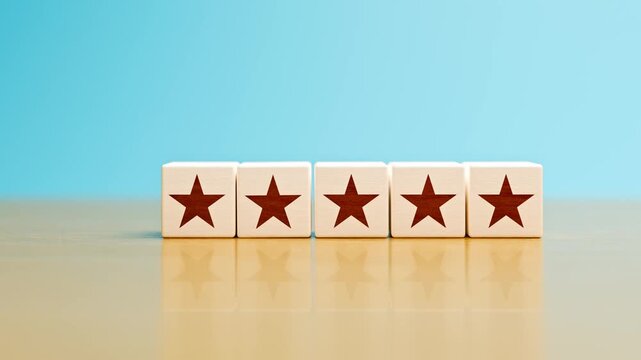 Concept: 5 star rating. Five wooden cubes with a star falling into place in a row on a wooden table. Selective focus and copy space. Zoom in