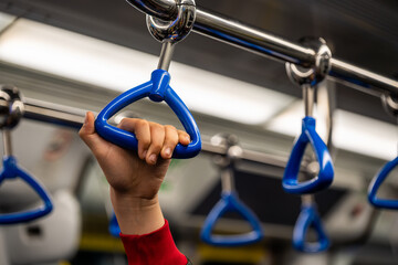 hand holding a blue subway handle during public transport commute. urban mobility concept showing everyday travel, safety and modern city lifestyle inside a metro train