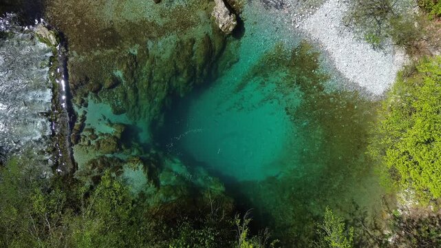 Aerial top view of turquoise spring water surrounded by lush green forest, Oko Skakavice in Montenegro, 4k
