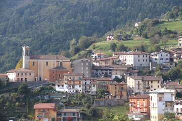 igh-angle panoramic view of the alpine village of Lodrino, situated in the Val Trompia valley, Brescia province. The images capture the traditional Italian mountain architecture, green hillsides