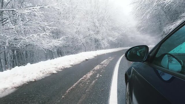 Driving on snow covered closed mountain road with pine tree forest