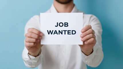 Individual holding a sign that reads job wanted, showcasing determination and readiness for new employment opportunities in a professional setting