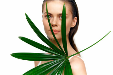 Elegant portrait of a woman holding a green leaf, showcasing natural beauty and freshness in a minimalist style.