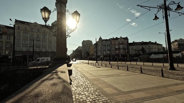 Timelapse of Lions Bridge in Sofia, Bulgaria, on a sunny day, showing stone pillars, street lamps, cobblestone pavement, pedestrians, lion statues, and surrounding historic buildings, BG, 01 Jan. 2026