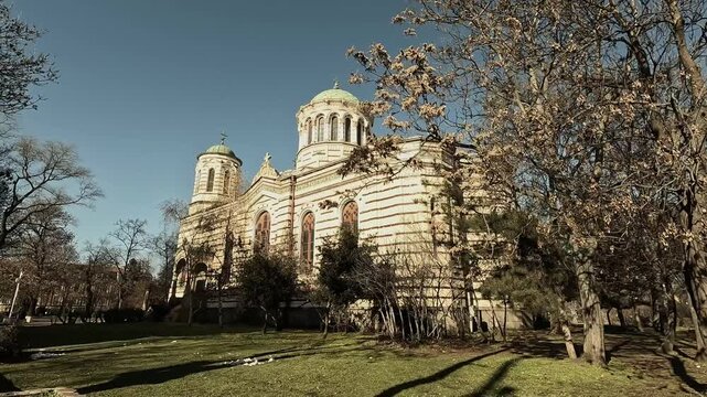 Handheld winter video of St. Nicholas Church in Sofia, Bulgaria, filmed from the side and back, showing its yellow-brown striped facade, arched windows, and entrance, BG, 01 Jan. 2026