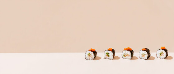 Row of sushi rolls along bottom edge on beige background with copy space