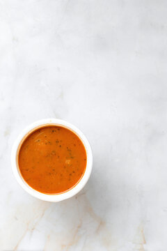 Hot tomato soup in delivery bowl on marble background
