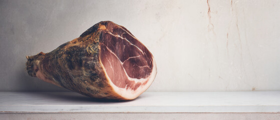 Whole cured ham leg on marble surface
