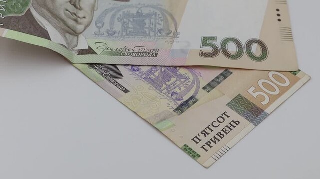 Ukrainian 500 Hryvnia banknotes scattered on white. This footage is suitable for finance, economy, wealth, or business concepts.