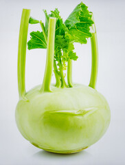 Fresh kohlrabi, pale green bulb with protruding stems and crisp texture, isolated on pristine white background.