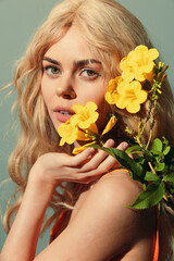 Beautiful model with blonde hair holding yellow flowers, showcasing a vibrant spring vibe and soft emotions against a pastel background.