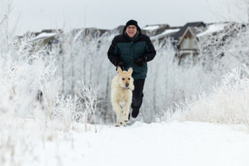 man playing with his dog outside in the snow