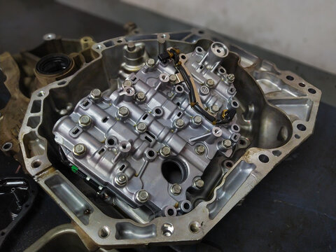 Internal view of an automatic gearbox housing showing the complex valve body and solenoids during an automotive transmission overhaul.