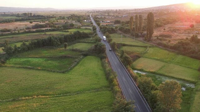 Huge semi-trailer cargo truck drive on the rural road at sunset, sunrise, aerial shot