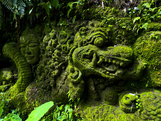 Ancient mossy relief depicting mythological figures in Bali, Indonesia