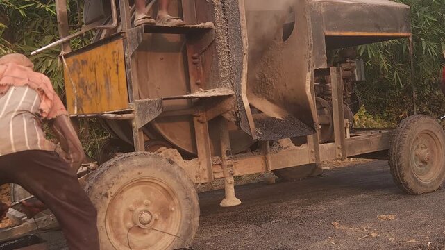 Workers using a machine to mix asphalt, Close up of a Bitumen Mixing Machine OR Asphalt Mixer, it is widely used in India and road construction contexts.
