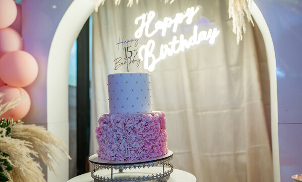 Pastel de cumplea&ntilde;os de quince a&ntilde;os con dise&ntilde;o elegante en tonos rosados y fondo iluminado