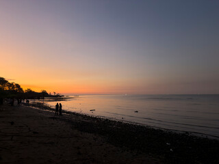People silhouetted on beach at colorful Indonesia sunset