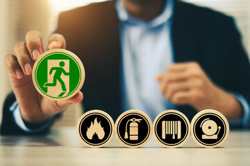 Hand chooses door exit sing on wooden toy stack for fire escape to prevent with fire extinguisher and emergency prevention protection symbol for safety first and rescue and training concepts.