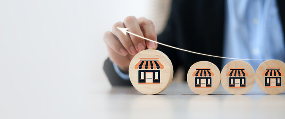 Businessman's hand chooses wooden toy stack with franchise icon for goal to growth is investment planning financial and branch expansion and management bank loans for marketing franchising.