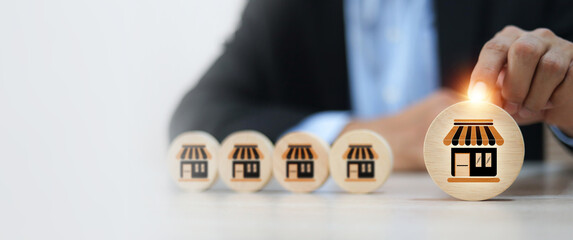 Businessman's hand chooses wooden toy stack with franchise icon for goal to growth is investment planning financial and branch expansion and management bank loans for marketing franchising.