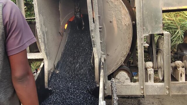 Workers using a machine to mix asphalt, Close up of a Bitumen Mixing Machine OR Asphalt Mixer, it is widely used in India and road construction contexts.