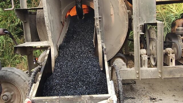 Workers using a machine to mix asphalt, Close up of a Bitumen Mixing Machine OR Asphalt Mixer, it is widely used in India and road construction contexts.