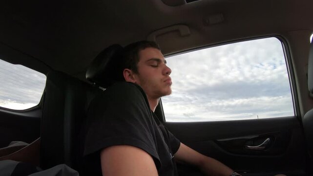 Tired man, passenger sleeping in the backseat of a car while riding in a car driving on a highway through the Nevada desert