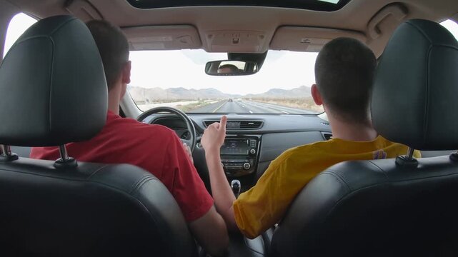 Happy tourists friends driving car on the highway towards Los Angeles, Nevada, USA. Dancing and singing while driving. A USA road trip concept of young people having fun traveling together
