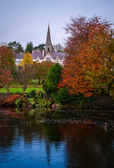 Obraz premium Autumn foliage and a church spire rising over the forested River Lee at Fitzgerald Park in Cork, Ireland.