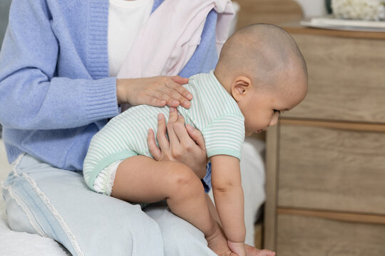 Careful mother burping little baby boy gently rubbing back to comfort gas pain after feeding bedroom showing childcare love nurture bonding peaceful calm relief parenting support infant digestion