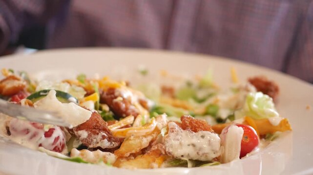 Man Eats Piece of Fried Chicken in Restaurant Salad