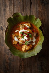 Top Down View of Traditional Spicy Curry Dish Served on Banana Leaf with Coconut Cream and Chili Garnish