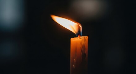 Burning Orange Candle Flame Close-Up in Dark Atmospheric Lighting