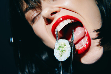 Bold woman with red lips passionately holding sushi with chopsticks, captured in a dramatic, close-up composition.