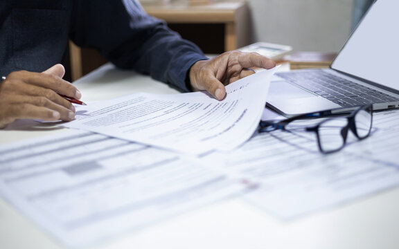 businessman or professional lawyer reviewing document at office. legal expert working with laptop checking financial documents and business contract