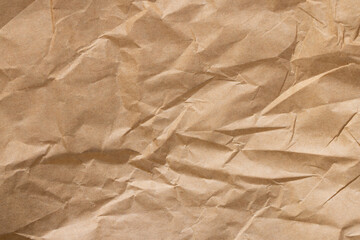 Fototapeta premium Crumpled brown kraft paper texture background, wrinkled recycled paper sheet,Top view of brown crumpled kraft paper texture background. A high-resolution close-up of wrinkled recycled paper sheet.