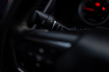 Close-up of car windshield wiper control stalk on steering wheel column,A detailed close-up shot of a modern vehicle's windshield wiper control lever, showing various settings like Mist, Off, and Low, © banjongseal324