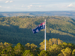 Scenic elevated views of the Australia flag on display at the Picnic Point public park area in Toowoomba with Table Top Mountain and the Bushland Reserve in the background, Queensland, Australia