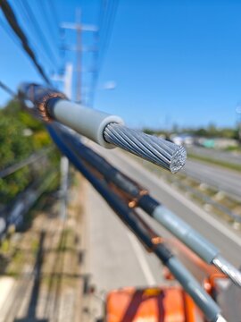 Close up detail of twisted aerial bundle cable texture showing black insulation and aluminum core for electric power distribution grid infrastructure background.
